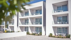 A modern multi-story hotel with balconies, outdoor seating, and a paved courtyard.
