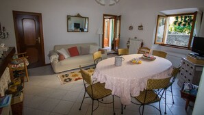 A cozy living room with a round dining table, wicker chairs, a sofa, and a television.