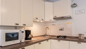 A modern kitchen with white cabinets, a microwave, a coffee maker, a sink, and a stove. - Ca' Molin, view on the Venetian canals (Venezia)