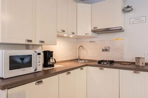 A modern kitchen with white cabinets, a microwave, a coffee maker, a sink, and a stove. - Ca' Molin, view on the Venetian canals (Venezia)