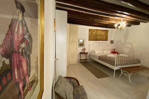 A bedroom with a bed, a nightstand, a chair, a painting, and a ceiling with exposed beams. - Ca' Molin, view on the Venetian canals (Venezia)