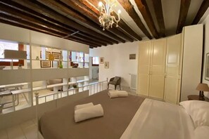 Une chambre d’hôtel avec un grand lit, un lustre, une armoire et un balcon avec vue.