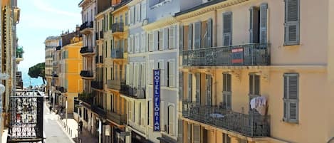 A row of multi-story buildings with balconies, a visible hotel sign, and a clear view of the street.