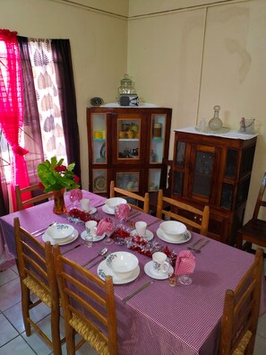 A dining area with a checkered tablecloth, wooden chairs, and a cabinet with glass doors.