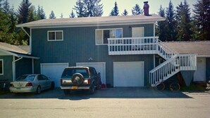 Ein zweistöckiges Haus mit Garage, Balkon und einer Treppe, die zum oberen Stock führt.