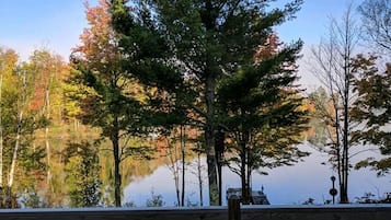 Enjoy a serene waterfront view from this deck overlooking a tranquil body of water surrounded by trees.