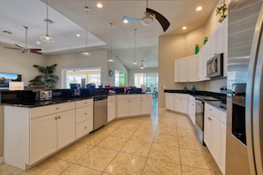 Enjoy a spacious kitchen with ample counter space, microwave, and dishwasher, illuminated by pendant lights and a ceiling fan.