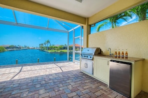 Enjoy the serene view of the water from this kitchen, featuring a gas stove and stainless steel appliances.