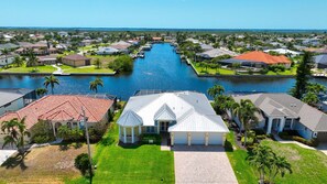 Stunning homes line a tranquil waterway, surrounded by lush lawns and palm trees.