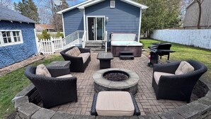 Eine Terrasse mit Korbmöbeln, einer Feuerstelle und einem Whirlpool.
