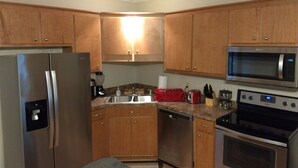 A modern kitchen with wooden cabinets, stainless steel appliances including a refrigerator, microwave, and oven, and a granite countertop. - Great Apartment in Historic Downtown Columbus. (Columbus)