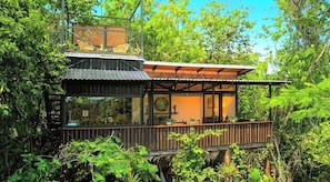 Uma casa moderna com deck de madeira, janelas amplas e vista para o verde ao redor.
