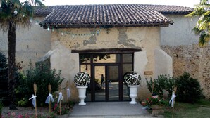 A building with a tiled roof, a central entrance with glass doors, and a pathway leading to it.
