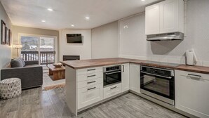 A modern kitchen with white cabinetry, a wooden countertop, and built-in ovens. - 2bd_mw_315 (Frisco)