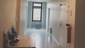 A hallway with a table, a window, a door, and a fire extinguisher. - Le Presbytère (Hontanx)