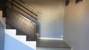 A staircase with a metal handrail, white steps, and a wall-mounted light fixture. - Le Presbytère (Hontanx)