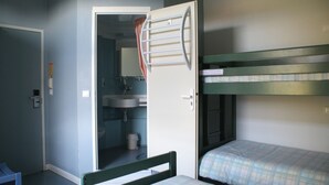 A small, compact room with bunk beds, a single bedside table, a chair, and a bathroom with a sink and toilet. - Le Presbytère (Hontanx)