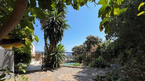 A garden with a palm tree, a pool, and a view of the sea. - Very nice villa with infinity pool, sea view, harbor, Cavalaire (Cavalaire-Sur-Mer)