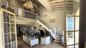 A spacious living area with a high ceiling, a staircase, and a view of the outdoors. - Very nice villa with infinity pool, sea view, harbor, Cavalaire (Cavalaire-Sur-Mer)
