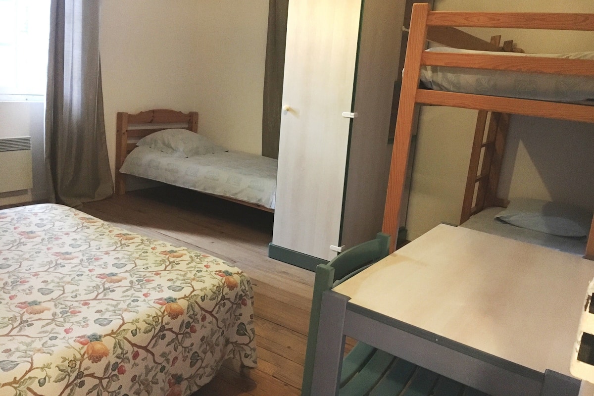 A room with a bed, a bunk bed, a desk, and a wardrobe.