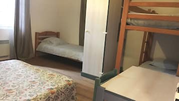 Una habitación con una cama, literas, un escritorio y un armario.