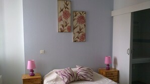 A bedroom with a bed, two nightstands, a dresser, and two wall-mounted lamps.