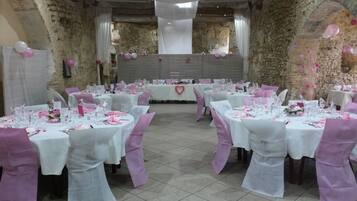 A banquet hall with round tables set for a formal event, featuring white tablecloths and pink accents.