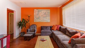 Una sala de estar con un sofá, sillones, una mesa de centro y un cuadro en la pared.