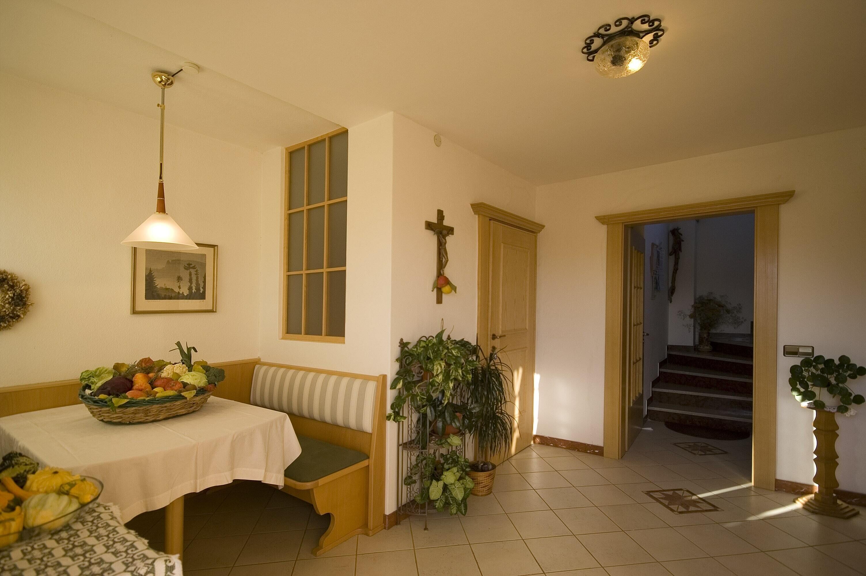 A dining area with a table set for a meal, a bench, and a wall-mounted cross.