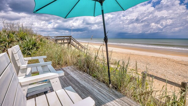 A wooden deck with benches overlooking a beach.
