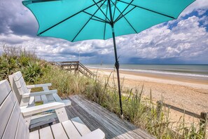 Une terrasse en bois avec des bancs donnant sur une plage.