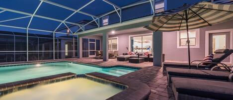 Un área de piscina exterior cubierta con sillas de descanso y una mesa de patio.