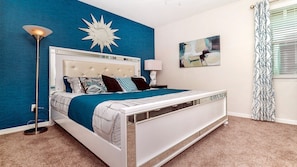 A modern bedroom with a tufted headboard, a large bed, a floor lamp, and a star-shaped wall decoration.