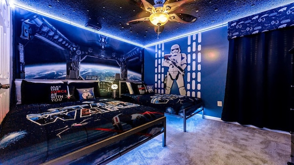 A room with a bed, a desk, and a wall mural.