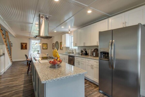 A modern kitchen with white cabinets, a stainless steel refrigerator, and a granite countertop.