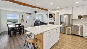 A modern kitchen with white cabinets, stainless steel appliances, and a wooden island.