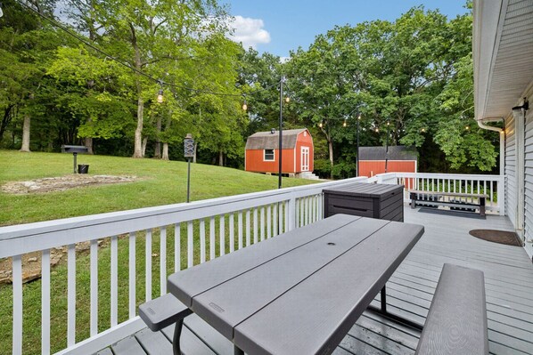 A deck with picnic tables and a red barn in the background.
