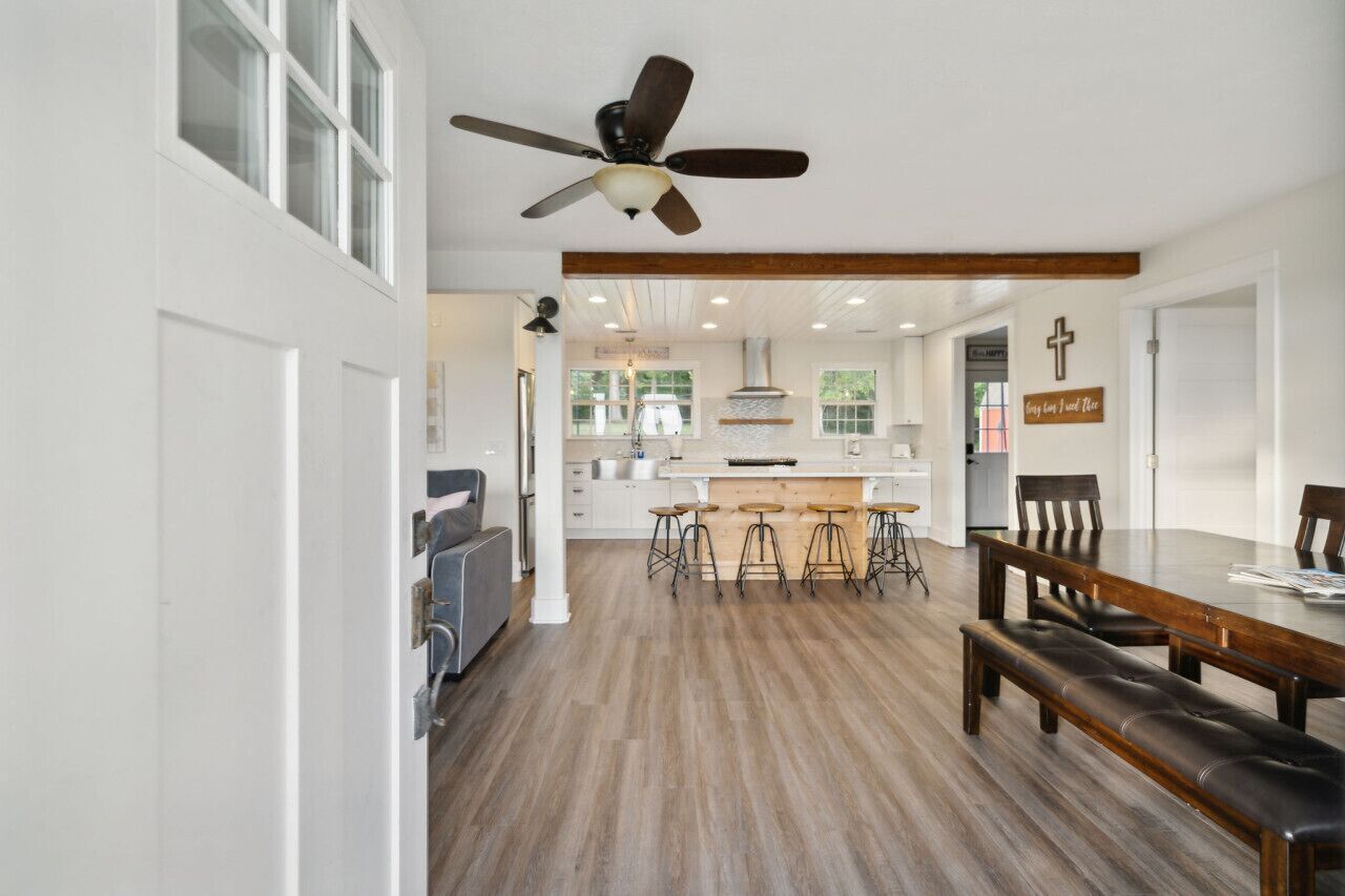 A spacious kitchen with a central island, bar stools, and a dining table with benches.