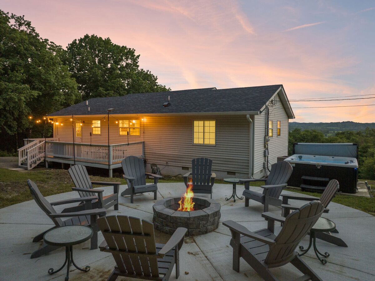 A house with a deck, outdoor seating, a fire pit, and a hot tub.