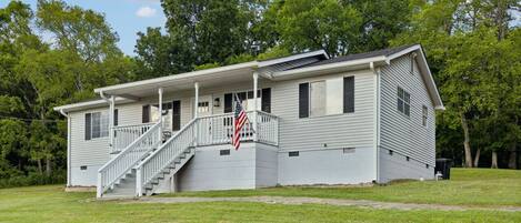 Ein eingeschossiges Haus mit Veranda, Treppe und einer US-amerikanischen Flagge.