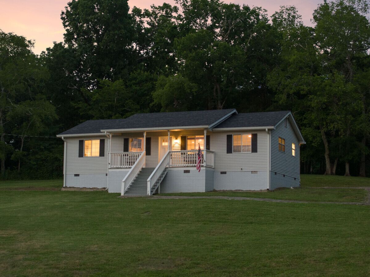 Una casa a un piano con veranda, una scalinata e una bandiera americana.