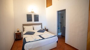 Un lit bien fait, avec des oreillers, une lampe de chevet et un luminaire fixé au mur.