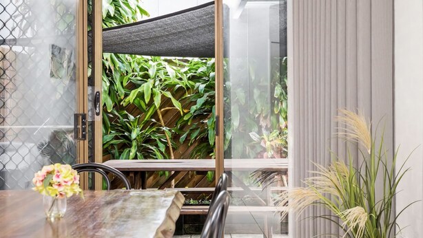 Un espace repas moderne avec une cloison en verre, une table en bois et un vase de fleurs.