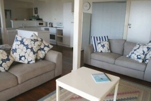 A living room with two sofas, a small table, and a kitchen in the background.