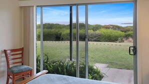 A room with a sliding glass door leading to a grassy outdoor area with a view of trees and hills. - Paradise Court 6, Tura Beach (Tura Beach)