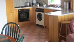 A kitchen with wooden cabinets, a stove, a dishwasher, and a sink. - Town House, situated in the village Salthill close to the seafront. (Galway)