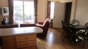 A kitchen with wooden cabinets, a dining table with chairs, a sofa, and a television. - Town House, situated in the village Salthill close to the seafront. (Galway)