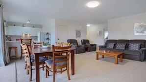 A living room with a dining table, chairs, a sofa, and a coffee table. - North Terrace 9 (Merimbula)