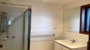 A bathroom with a glass-enclosed shower, a white sink, and a mirror above it.