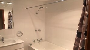 Ein Badezimmer mit Badewanne, Dusche, Waschbecken und Spiegel.